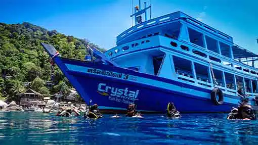 Scuba divers on water surface with Crystal dive boat at the Best place to learn to dive in Thailand