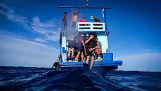 kohtaodiving.org-multilevel-diver-specialty-course-diver-jump Crystal dive boat seen from the back with divers entering the water