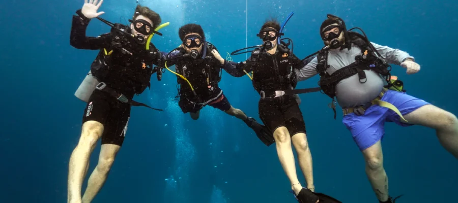 chronicles learn to scuba dive on koh tao divers and instructor Two students learning to dive on Koh Tao and Instructor waving at the camera